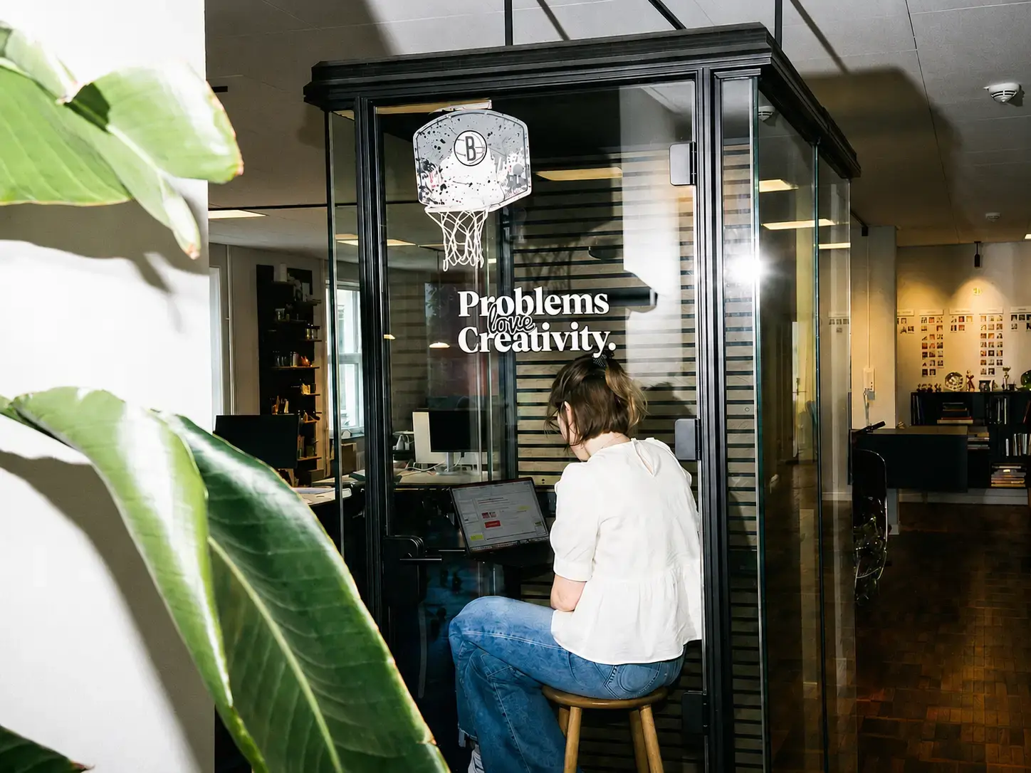 A person working in a glass phone booth that reads 'Problems love Creativity.'